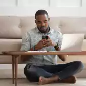 man sitting cross legged reviewing email