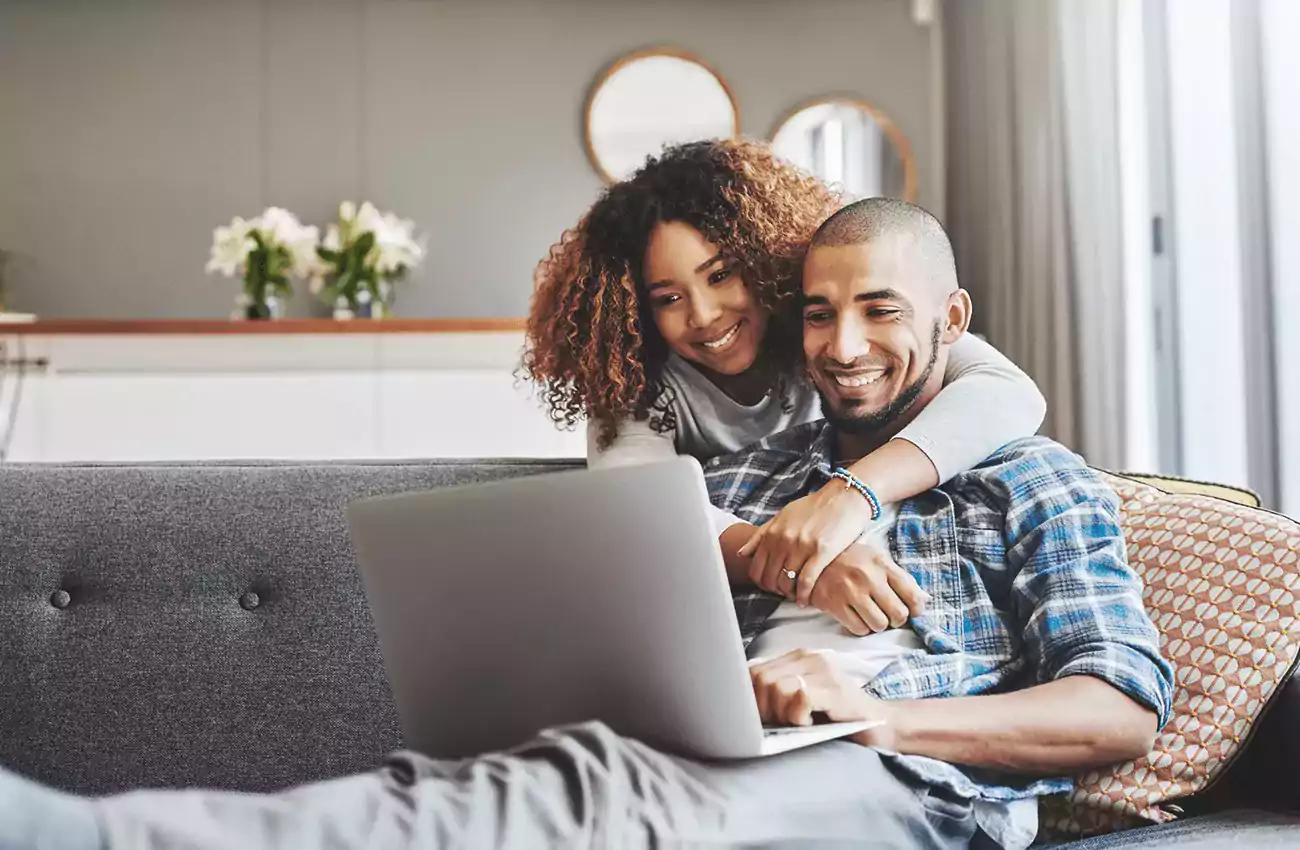 couple smiling looking at laptop